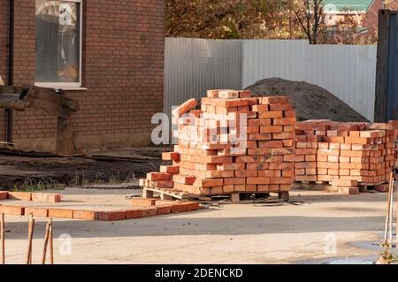 Red clay bricks are stacked on wooden pallets. Stock Photo