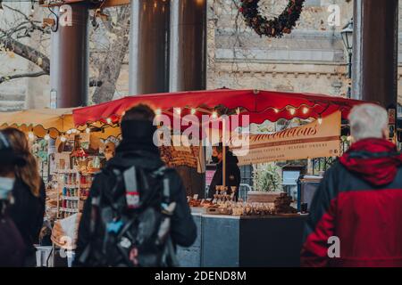 London, UK - November 19, 2020: Seller wearing a protective face mask at the stall inside Borough Market, one of the largest and oldest food markets i Stock Photo