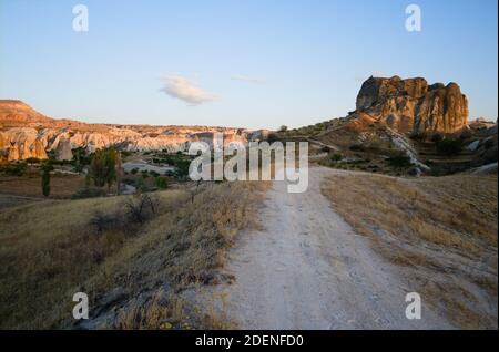 Dirt road in desert mountain landscape in Cappadocia. Sandstone hill illuminated with sunset light. Cappadocia, Anatolia, Turkey. Stock Photo