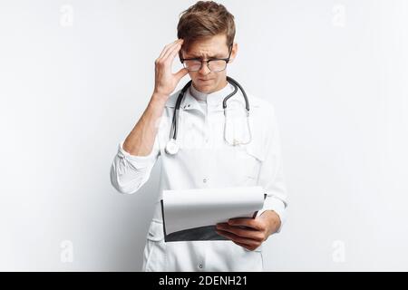 Thoughtful doctor, looking at the documents, and makes notes in the documents, a young student with a folder in his hands, on a white background, Stock Photo