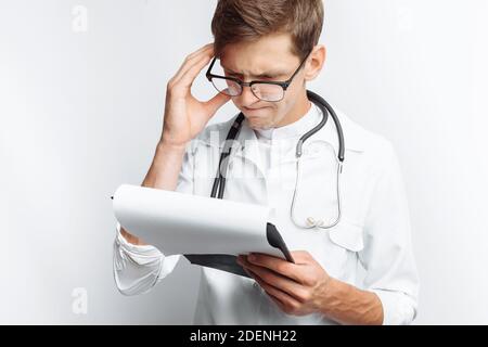 Thoughtful doctor, looking at the documents, and makes notes in the documents, a young student with a folder in his hands, on a white background, Stock Photo