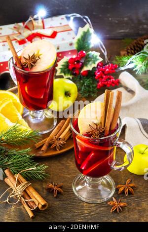 Mulled wine in glass mug with spices on rustic table. Winter Christmas hot drink with orange, apple and spices. Stock Photo