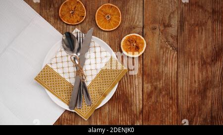 Overhead view of fall Thanksgiving or Christmas table setting over wooden table with copy space. White plate with dry oranges Stock Photo