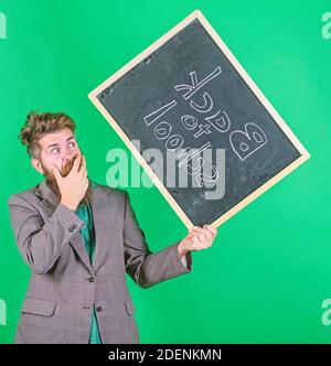 Keep working. Teacher with tousled hair stressful about school year beginning. Teacher bearded man holds blackboard with inscription back to school green background. Teaching stressful occupation. Stock Photo
