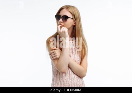 Portrait of an emotional stylish girl who thinks of something, the model poses in glasses on a white background Stock Photo