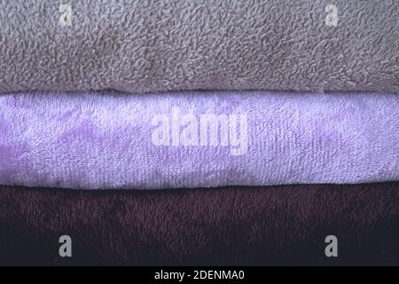 Winter blanket on a wooden table. Clothes with different patterns of fabric folded in pile. Winter bedding. Stock Photo