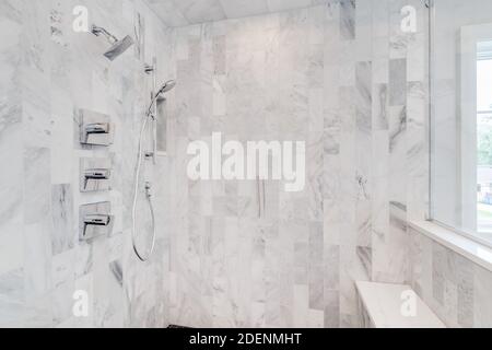 The interior of a gorgeous marble tiled shower with chrome faucet and a seat. Stock Photo