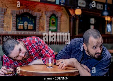 Two male friends drinking whiskey together at the pub. Best friends, joking and having a good time. Stock Photo