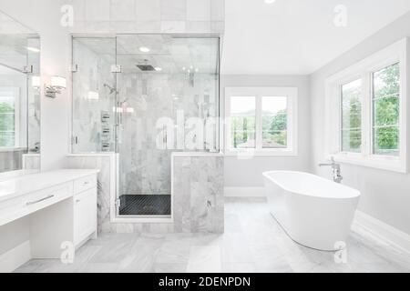 https://l450v.alamy.com/450v/2denpdn/a-large-luxurious-bathroom-with-a-stand-alone-tub-white-vanity-and-a-glass-stand-up-shower-with-marble-tiles-and-bench-seat-2denpdn.jpg