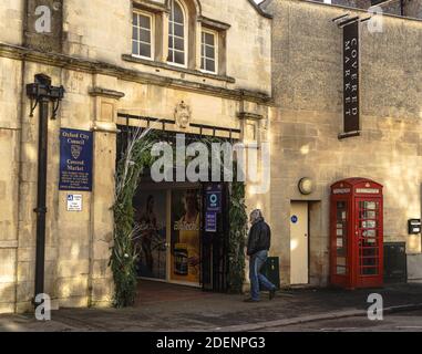 A middle aged man dressed in jeans and a leather jacket, walks towards the decorated entrance to The Covered Market, Oxford, UK. Christmas. Stock Photo