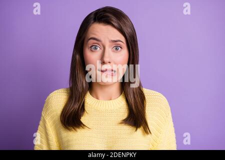 Photo portrait of stressed guilty female student biting lip looking upset wearing yellow sweater isolated on bright color purple background Stock Photo
