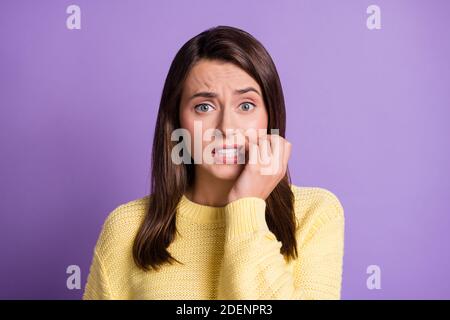 Photo portrait of guilty worried brunette girl biting fingers wearing casual knitted sweater isolated on vivid color violet background Stock Photo
