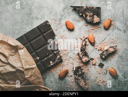 Dark chocolate bar and Broken chocolate pieces and almonds on gray background Stock Photo