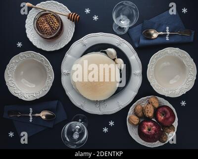 Christmas table with decoration, wafers, honey, garlic bulbs, apples and walnuts. Place setting for two. Overhead view. Stock Photo