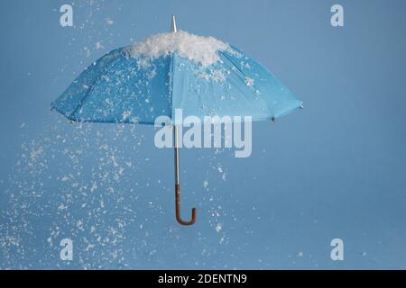 Blue umbrella on blue background with snow. Blue monday concept. Stock Photo