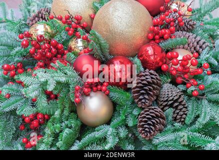 Christmas composition with red berries, green spruce branches, Christmas balls and pine cones. New Year's holiday decor. Stock Photo