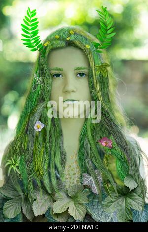 Young beautiful girl with hair made of grass and dress made of leaves. Ecology concept. Stock Photo