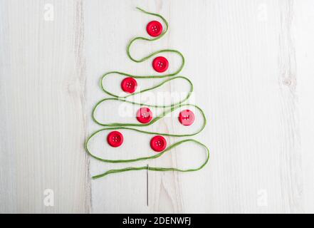 Sewing theme creative flat lay design: Christmas tree made of needle, thread and buttons on wooden surface Stock Photo