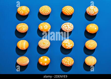 Orange colored Easter eggs pattern on contrasting blue background Stock Photo