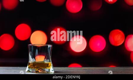 Whiskey in a glass on a background of bokeh circles, an alcoholic drink in a glass on a black background with red circles. Bar counter with drinks. Stock Photo