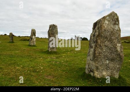 A portion of the Late Neolithic or Early Bronze Age prehistoric  Hurlers stone circle on Bodmin Moor with the ruins of a tin Mine engine house in the Stock Photo