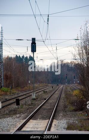 Railway tracks with overhead lines and red traffic lights in portrait format Stock Photo