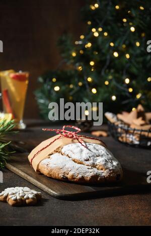 Traditional Christmas stollen on festive table with garland and evergreen branches. Stock Photo