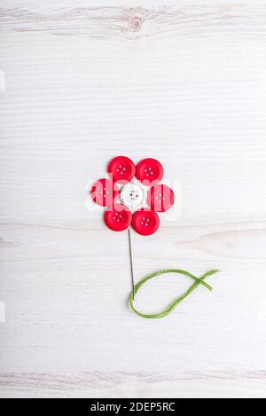 Sewing theme creative flat lay design: flower made of needle, thread and buttons on wooden surface Stock Photo