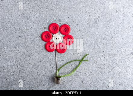 Sewing theme creative flat lay design: flower made of needle, thread and buttons on grey surface Stock Photo