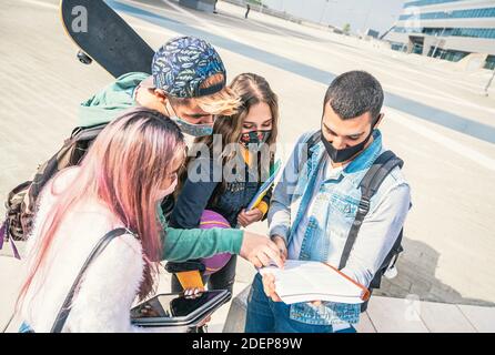 Multiracial students with face mask studying at college campus park in the pandemic time - New normal lifestyle concept with young students having fun Stock Photo