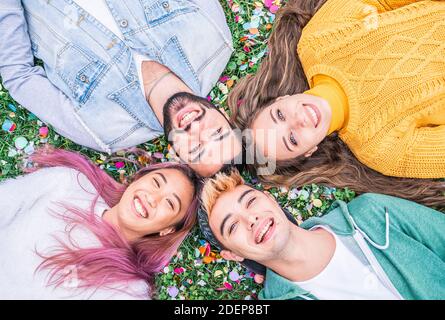 Happy smiling young people taking selfie looking in the sky  lying on the grass at park - Happy friendship concept with young students having fun toge Stock Photo