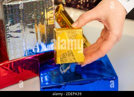 Young womans hand holding a gift box surrounded by gift boxes Stock Photo