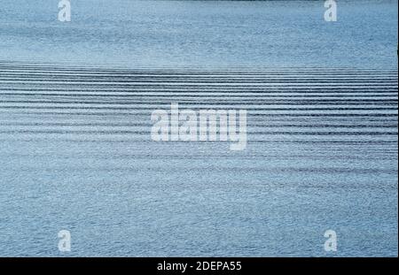 Abstract horizontal ripples across tranquil blue water surface background Stock Photo
