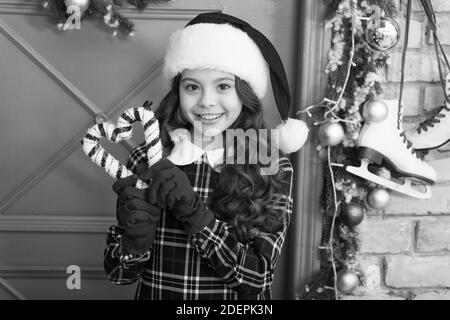 Christmas decor. Peppermint candy. Decorating ideas. Child hold christmas candy cane. Striped candy cane traditional winter holidays. Elegant happy kid in hat and gloves. Waiting for Santa Claus. Stock Photo