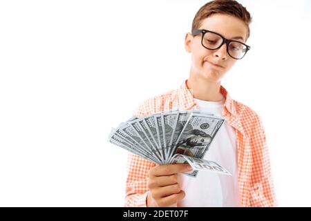 A young man with glasses thought about what to do with a large number of bills a hundred dollars, a portrait of a successful teenager in a shirt in th