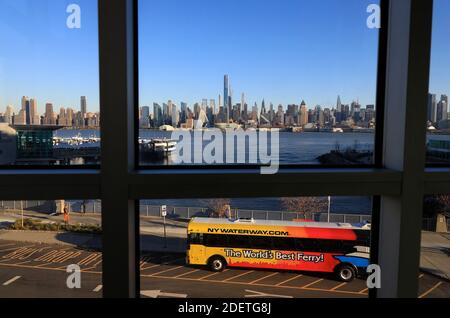 The view of Manhattan skyline and Hudson River from a street overpass near Port Imperial Ferry Terminal with a NY Waterway shuttle bus in foreground.Weehawken.New Jersey.USA Stock Photo
