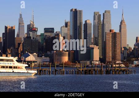 View of Midtown Manhattan with Empire State Building and other high-rises with a NY Waterway ferry boat in foreground from Weehawken.New Jersey.USA Stock Photo