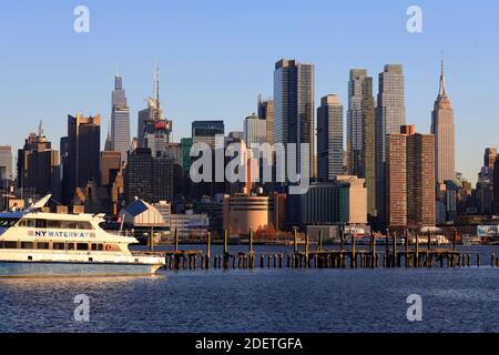 View of Midtown Manhattan with Empire State Building and other high-rises with a NY Waterway ferry boat in foreground from Weehawken.New Jersey.USA Stock Photo