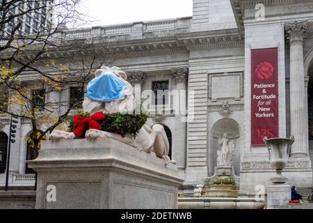 Lion in front of the New York Public Library wears a face mask and Holiday Wreath  during the coronavirus pandemic, NYC