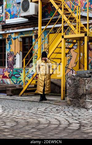 An older woman in a yellow coat is talking on the phone Stock Photo