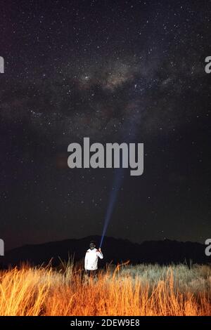 young man in the field observing the milky way with a flashlight in hi Stock Photo