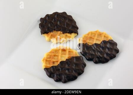 Three dark chocolate dipped waffle cookies on white snack plate Stock Photo