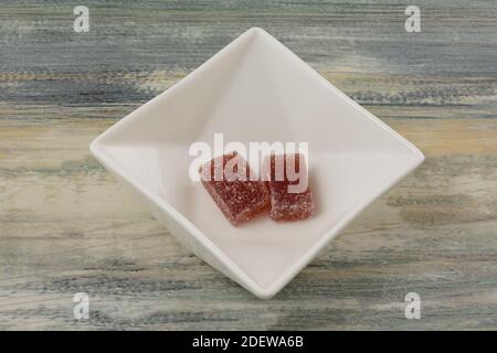 Two raspberry fruit juice jelly candy pieces encrusted with sugar in white candy dish on table Stock Photo