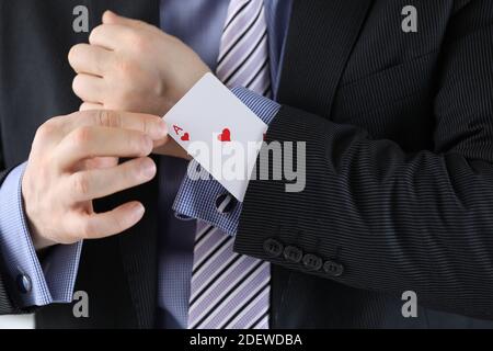 Man in suit puts ace of chirv card into sleeve of his jacket Stock Photo