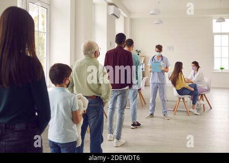Diverse people lining up waiting for their turn to get shots in modern vaccination center Stock Photo