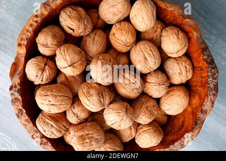Walnuts in a burr oak wooden bowl on a blue table Stock Photo