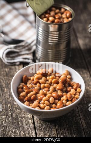 Mix of legume beans and chickpeas with sauce in bowl on wooden table. Stock Photo