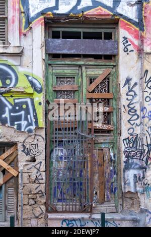 Athens, Greece , November 12, 2020. Wooden door ruined closed with planks and chains with padlocks at Monastiraki square area. Graffiti, street art on Stock Photo