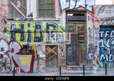 Athens, Greece, November 12, 2020. Graffiti on ruined wall, wooden door closed with planks and chains with padlocks at Monastiraki square area. Street Stock Photo