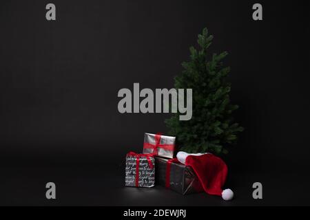 Christmas tree gift boxes and Santa hat on black background Stock Photo